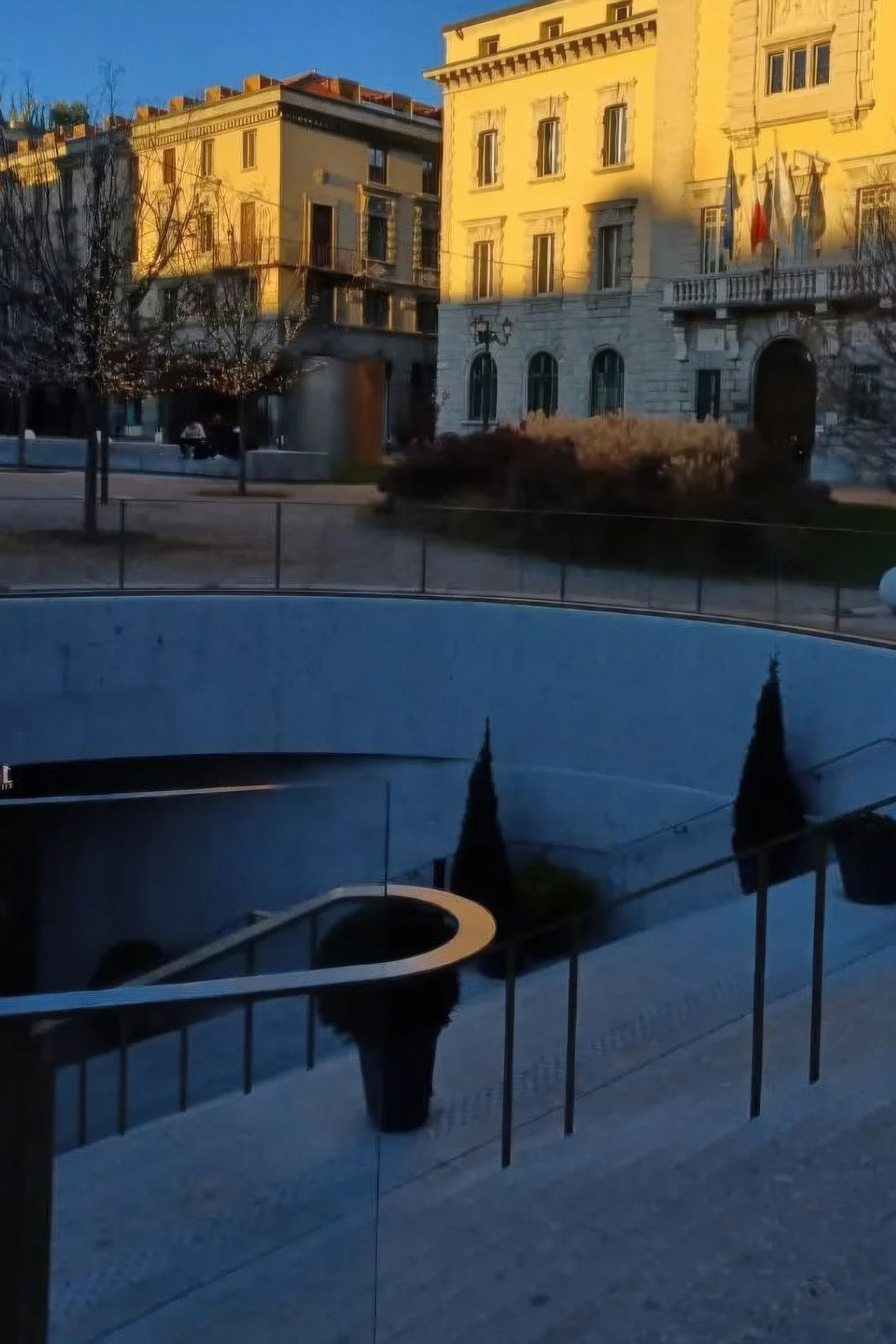 Vista al tramonto della piazza seminterrata con rivestimento curvilineo in Agglotech SB130 Aggloceppo levigato e sabbiato nel cuore del Centro Piacentiniano di Bergamo - Trapattoni Marmi