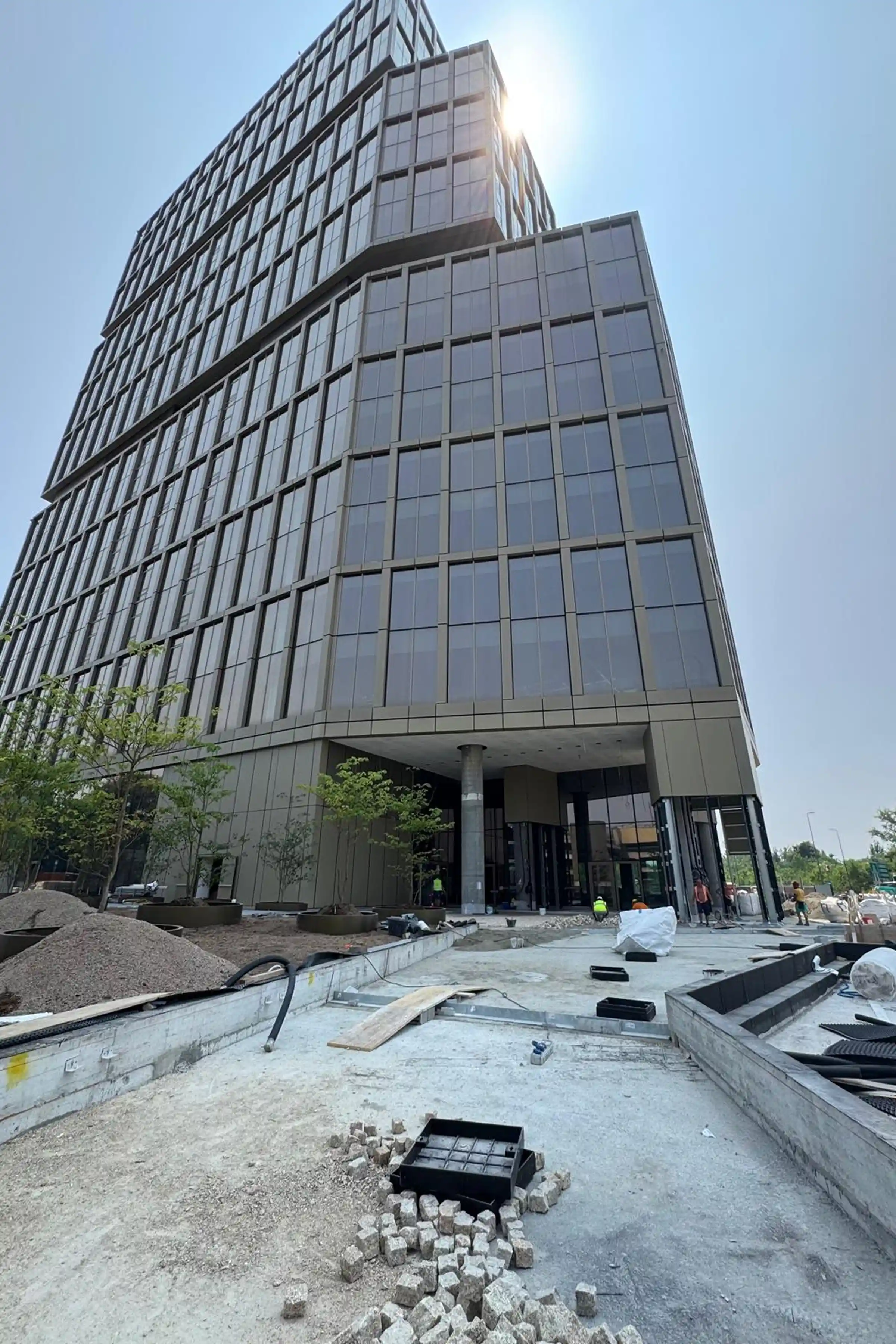 Vista della TheTris Tower durante il cantiere con cubetti in Granito Giallo pronti per la posa in opera nel giardino esterno a Famagosta Milano - Trapattoni Marmi